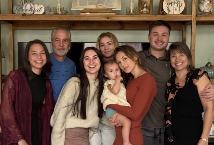 Family of eight smiling together for photo.